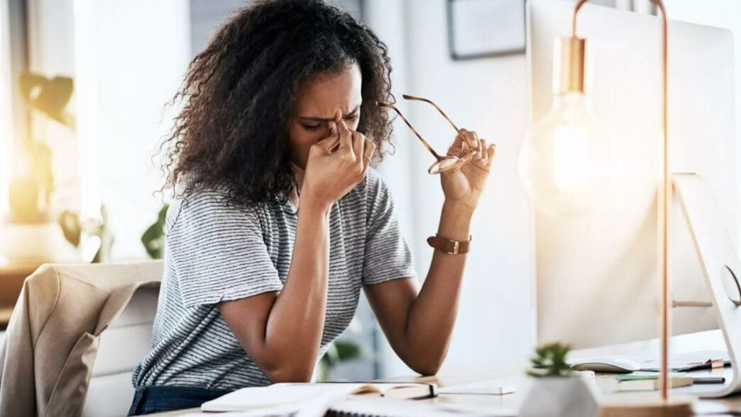 Bir kadın bilgisayar başında çalıştıktan sonra gözlerini ovuşturuyor