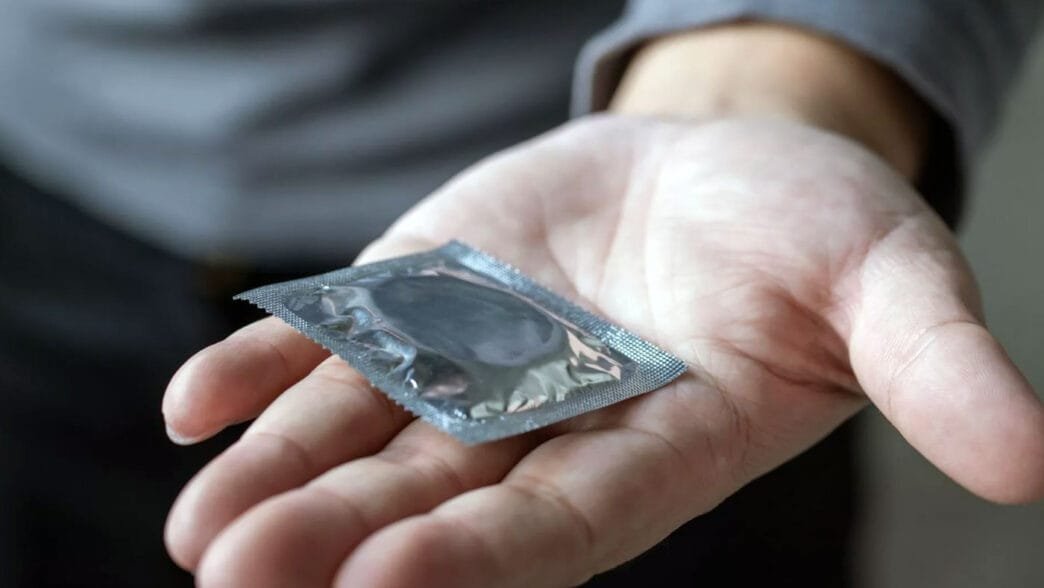 Bir adam prezervatif uzatıyor.